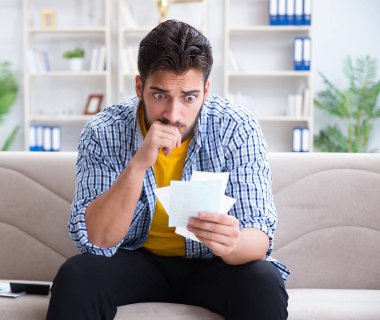 Ödeme yapması gereken faturalara kızgın bir adam.