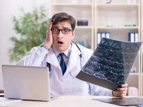 Médico joven mirando imágenes de rayos X en la clínica — Foto de Stock