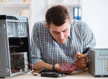 Genç teknisyen atölyede bilgisayar tamir ediyor.