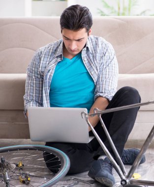 Evde bisiklet tamir eden genç bir adam.