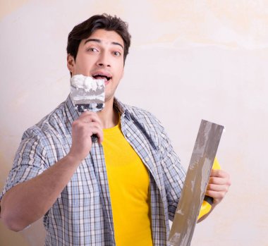 Evdeki duvara alçı yapıştıran genç adam.