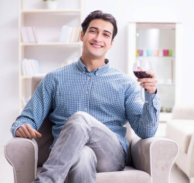 Genç adam evde şarap içiyor.