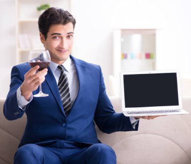 İş adamı evde oturmuş şarap içiyor.