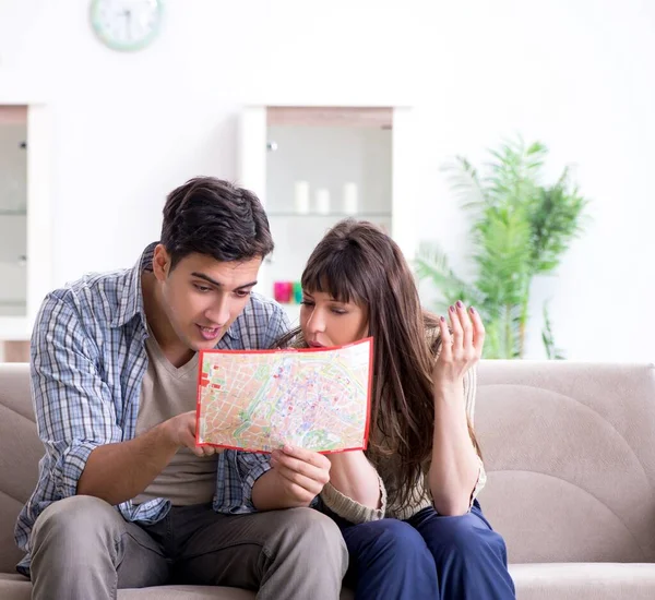 Ung familj diskuterar resplaner med karta — Stockfoto