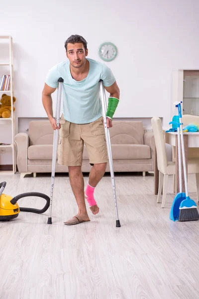 Jovem homem ferido limpando a casa — Fotografia de Stock
