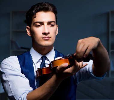 Genç müzisyen evde keman çalıyor.