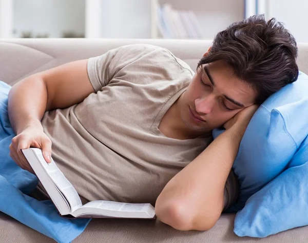 Jovem estudante se preparando para exames universitários na cama com livro — Fotografia de Stock