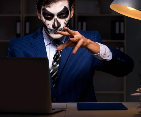 Бізнесмен з лякаючою маскою для обличчя, що працює пізно в офісі — стокове фото