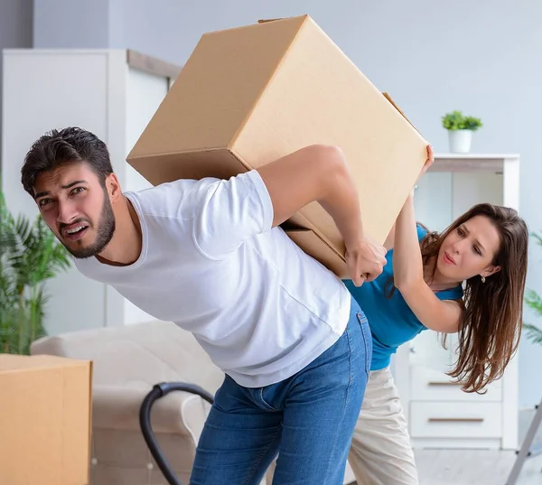 A jovem família desempacotando em nova casa com caixas — Fotografia de Stock