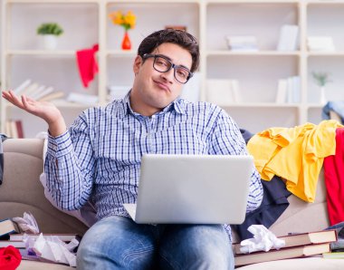 Genç adam dağınık bir odada çalışıyor.