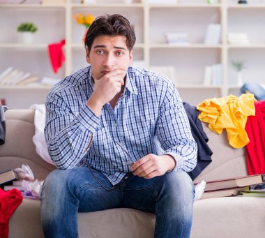 Genç adam dağınık bir odada çalışıyor.