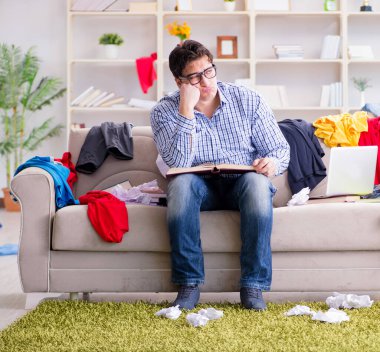 Genç adam dağınık bir odada çalışıyor.