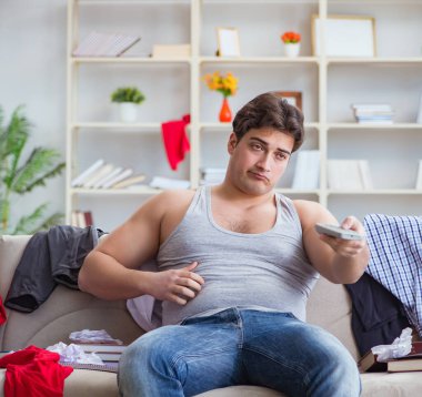 Genç adam dağınık bir odada çalışıyor.