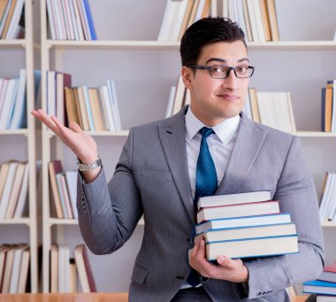 Kütüphanede çalışan yığınla kitabı olan bir işletme hukuk öğrencisi.
