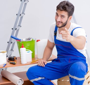 Tamirci, duvar kağıdıyla evde tadilat yapıyor.