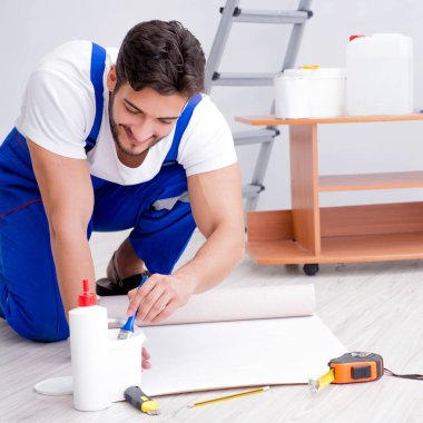 Tamirci, duvar kağıdıyla evde tadilat yapıyor.