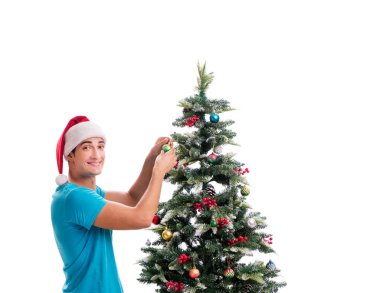 Genç adam beyaz üzerine izole edilmiş noel ağacını süslüyor.