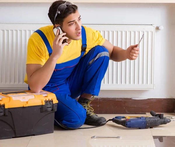 El joven reparador contratista reparando el panel de calefacción — Foto de Stock