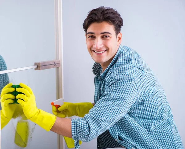 The young man cleaning mirror at home hotel — Stock Photo, Image