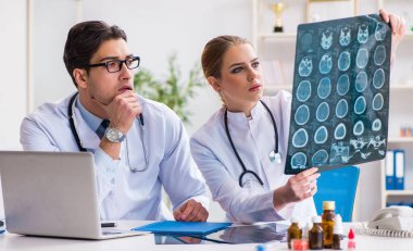 İki doktor teşhis için hastanın röntgen görüntülerini inceliyor.