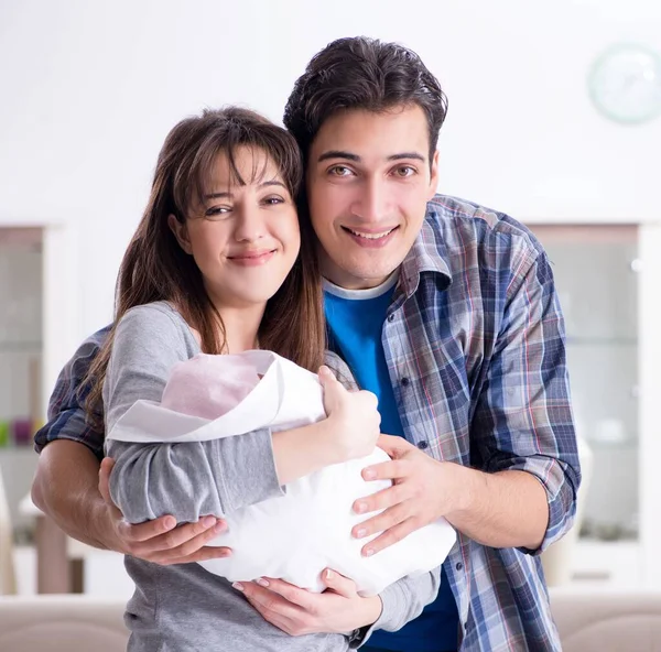 Young parents with their newborn baby near bed cot — Stock Photo, Image