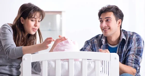 Padres jóvenes con su bebé recién nacido cerca de la cuna —  Fotos de Stock