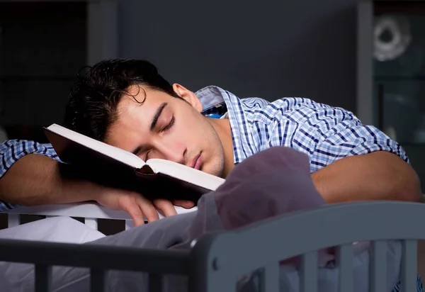 Young student doing homework and looking after newborn baby — Stock Photo, Image
