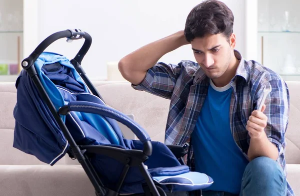 Junger Vater baut Kinderwagen zu Hause zusammen — Stockfoto