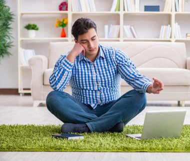 Genç yakışıklı adam evde yerde oturuyor.