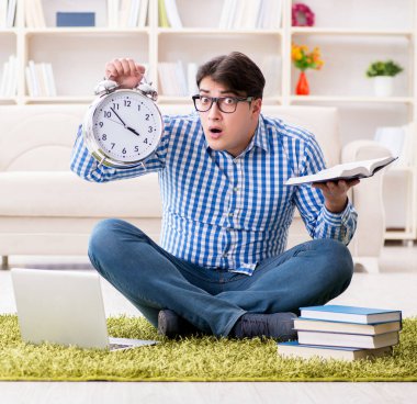 Genç yakışıklı adam evde yerde oturuyor.