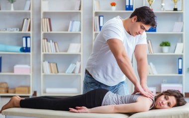 Genç doktor kayropraktik uzmanı kadın hastaya masaj yapıyor.