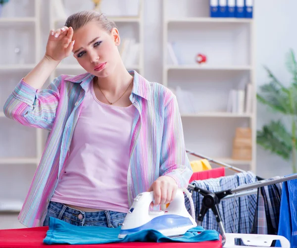 Droevige vrouw strijken kleding thuis — Stockfoto