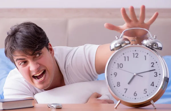 Man in bed frustrated suffering from insomnia with an alarm cloc — Stock Photo, Image