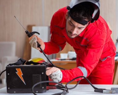 Kaynak tabancası elektrot ve kask takan genç bir tamirci.