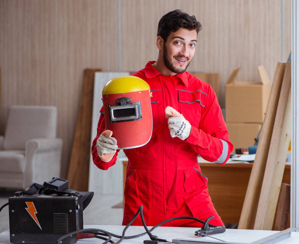 Young repairman with a welding gun electrode and a helmet weldin