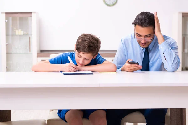 Zajęty ojciec pomaga synowi przygotować się do egzaminu — Zdjęcie stockowe