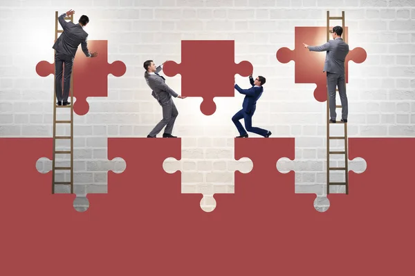 Uomo d'affari nel concetto di lavoro di squadra con puzzle — Foto Stock