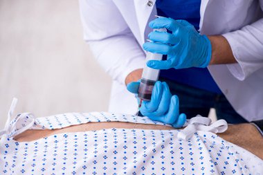 Yaşlı adam genç erkek stajyer doktoru ziyaret ediyor.