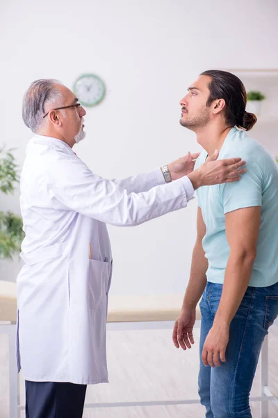 Young back injured man visiting experienced male doctor — Stock Image Young back injured man visiting experienced male doctor Stock Image
