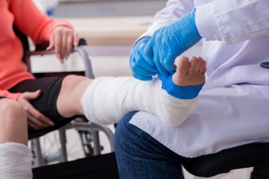 Genç bacak yaralı kadın yaşlı doktor travmatoloğu ziyaret ediyor.