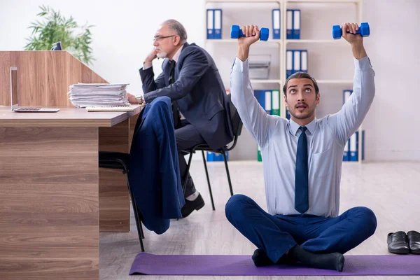 Dos empleados haciendo ejercicios físicos en el lugar de trabajo —  Fotos de Stock