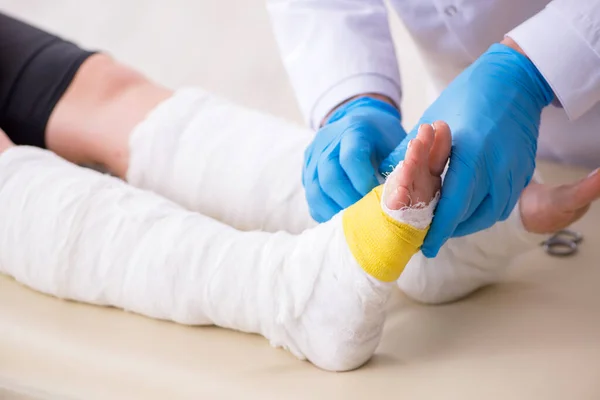 Jovem perna ferida mulher visitando médico velho traumatologista — Fotografia de Stock