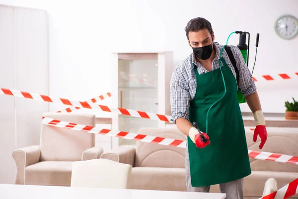 Young male sanitizer disinfecting indoors — Stock Photo, Image