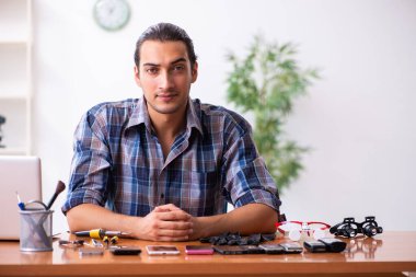 Cep telefonunu tamir eden genç bir teknisyen.