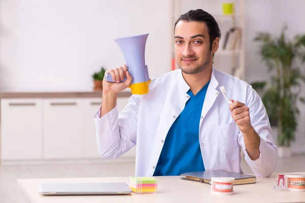 Jonge mannelijke tandarts werkzaam in de kliniek — Stockfoto