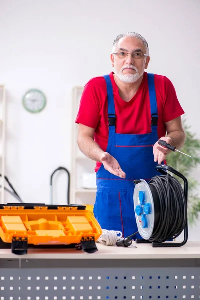 Viejo contratista sosteniendo carrete de cable en el interior — Foto de Stock