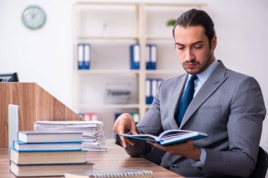 Genç erkek işadamı işyerinde kitap okuyor.