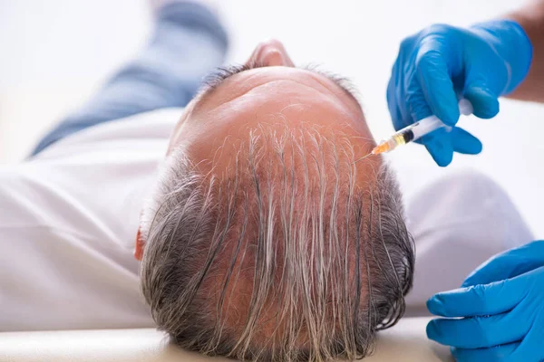 Old man visiting young male doctor in hair transplantation conce