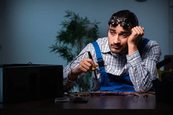 Jovem técnico do sexo masculino reparando computador na oficina à noite — Fotografia de Stock