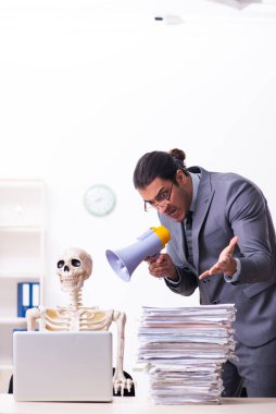 Genç erkek çalışan ve iskelet ofiste.